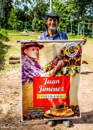 El agricultor miembro de Cenfrocafe Juan Jiménez sosteniendo un póster para su café orgánico de comercio justo.