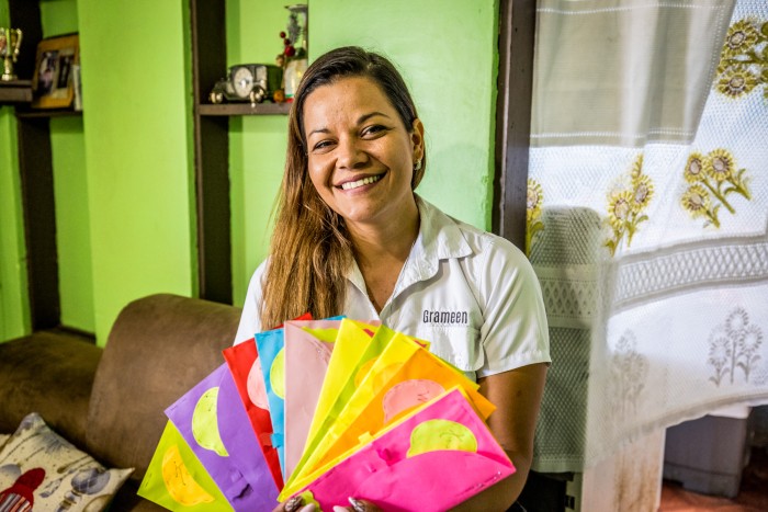 La gerente de Ventas de Grameen, Kristel Sancho, mostrando los sobres que contienen los ahorros de los miembros del grupo de Myriam.